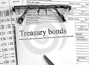 Paper with text Treasure Bonds on a financial tables with glasses