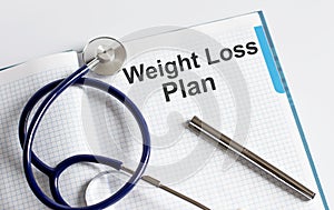 Paper with text WEIGHT LOSS PLAN on table with stethoscope