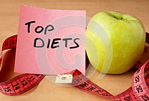 Paper with top diets, apple and measuring tape.