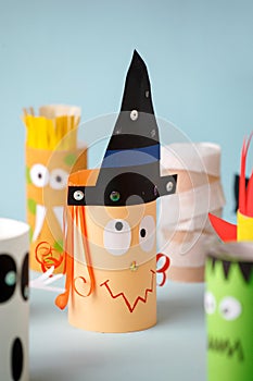 Paper toy witch for Halloween party. Easy crafts for kids on blue background, copy space, die creative idea from toilet tube,