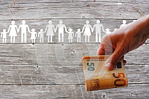 Paper white families on wooden background with Euros in hand