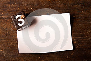 Paper and wooden cube with number on wooden table, 3