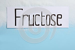 Paper with word Fructose and sugar on light blue background, flat lay. Space for text