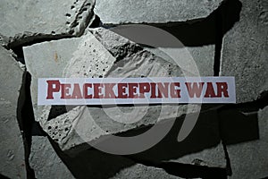 Paper with word Peacekeeping War on pieces of concrete, top view