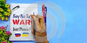 Paper with the words `SAY NO TO WAR, JUST PEACE` on blue background.