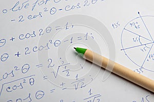 Paper with written mathematical calculations and pen, closeup