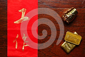 Paper wrote chinese text meaning of good wish beside plastic ancient chinese gold bar scene.