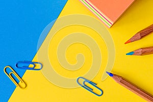 Paperclips, pencils and a memo block isolated against a blue and