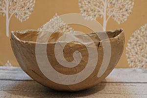 Papermache bowl on wooden top with yellow floral background.