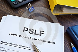 Papers foe Public Service Loan Forgiveness PSLF on the wooden surface.