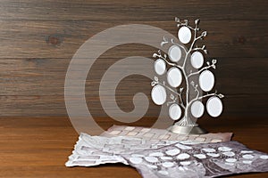 Papers and photo frame with family tree templates on wooden table. Space for text