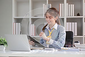 Paperwork. Happy smiling asian business woman in formal wear sitting at wooden desk in modern office and reading report