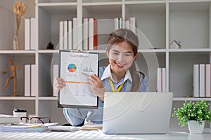 Paperwork. Happy smiling asian business woman in formal wear sitting at wooden desk in modern office and reading report