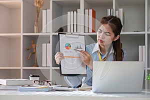 Paperwork. Happy smiling asian business woman in formal wear sitting at wooden desk in modern office and reading report