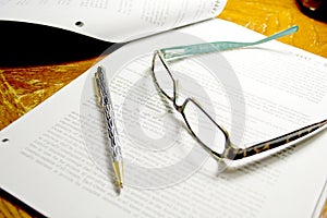 Paperwork with ready glasses and pen