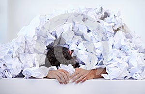 The paperworks piling up. a businessman buried under a pile of crumpled up paperwork.