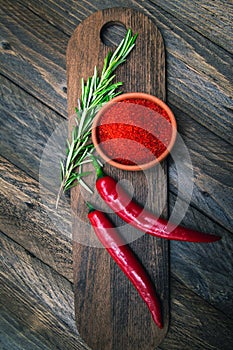 Paprika, chili peppers and rosemary on a wooden board