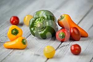 Paprika mix and cherry tomatoes, sweet mini red, yellow and orange peppers and green pepper on a wooden background