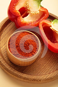 Paprika powder with fresh red pepper on beige background. Vertical photo
