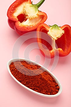 Paprika powder with fresh red pepper on pink background. Vertical photo