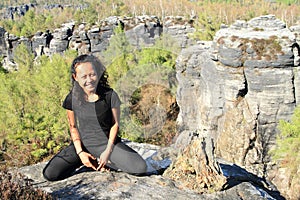 Papuan girl kneeling on rock in Czech Switzerland