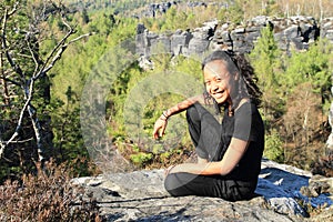 Papuan girl sitting on rock in Czech Switzerland