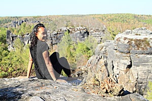 Papuan girl sitting on rock in Czech Switzerland