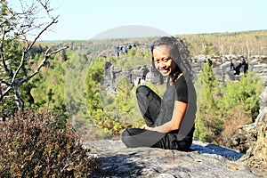 Papuan girl sitting on rock in Czech Switzerland