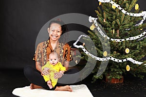 Papuan mom with baby by Christmas tree