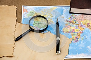 Papyrus on a world map, pen and magnifier