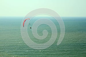 Para glider flying in blue sky over the ocean.