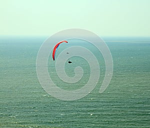 Para glider flying in blue sky over the ocean.