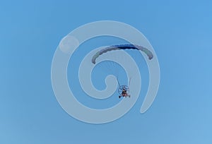 Para motor glider flying towards the moon