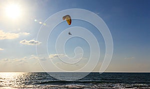 Parachute jumper on motorized parachute flying over the sea