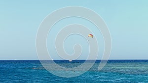 Parachute from kitesurfing hovers over the water`s edge against the clear blue sky. summer, seascape. water surface