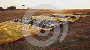 Parachute lying on the ground in the sunset rays of the sun on the airfield