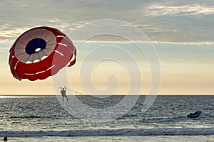 Parachute pushed by speedboat in the sea with sunset vacation