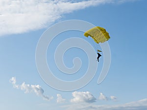 Parachuter descending with parachute against blue sky. Skydiver in the sky. People under parachute in the sky