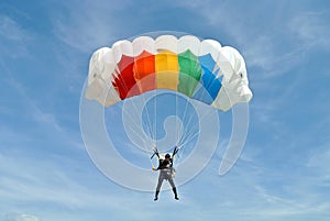 Parachuter, skydiver jumping and skydiving with colorful parachute in rainbow colours on parachuting cup, extreme sport