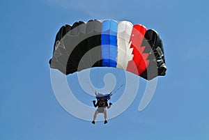 Parachuter, skydiver jumping and skydiving in parachute of black blue white red colours on parachuting cup, extreme sport