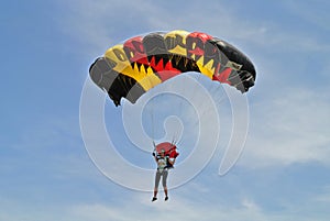 Parachuter, skydiver jumping and skydiving in parachute of black yellow red colours on parachuting cup, extreme sport