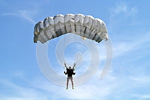 Parachuter, skydiver jumping and skydiving in parachute of grey color on parachuting competition, extreme sport