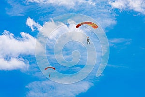 A parachutist against a background of blue sky and white clouds. Skydiving