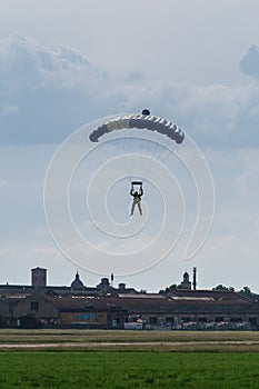 Parachutist with Blue Parachute near to the Ground Preparing for Landing