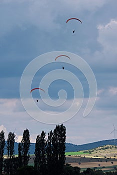 Parachutists approaching ground at cloudy sky