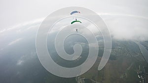 Parachutists flying in sky over green field. Extreme active sport. Tandem.