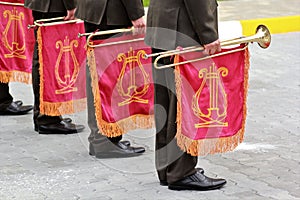 Parade of military orchestra holding musical instrument trumpet with red flag and golden lyre