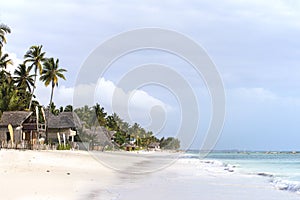 Paradise beach at Zanzibar island in Tanzania, Africa. White sand beach with buildings and palm trees, an amazing holiday