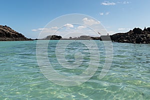 Paradise island of Lobos, Canary Islands, Spain. In the background, a person about to jump into the water from a small wooden