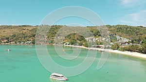 Paradisiac Ko Phi Phi Don Island Bay with boats moored over warm turquoise waters, Thailand - Aerial Fly-over showcase shot